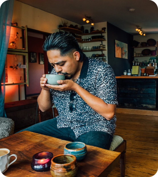 Photo of the owner of Nalu drinking a cup of kava and sitting at a low wooden table.